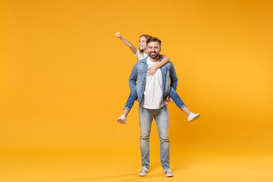 Smiling bearded man with child baby girl. Father little kid daughter isolated on yellow background. Love family parenthood childhood concept. Give piggyback ride to joyful sit on back clenching fist.