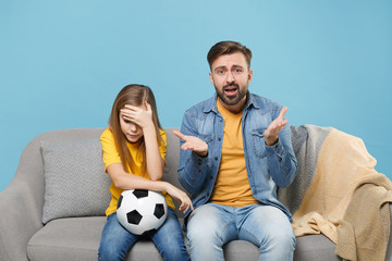 Displeased bearded man with child baby girl. Father little kid daughter isolated on pastel blue background. Love family parenthood childhood concept. Cheer up support favorite team with soccer ball.