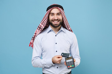 Smiling arabian muslim man in keffiyeh kafiya ring igal agal isolated on pastel blue background....