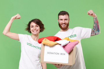 Cheerful friends couple in volunteer t-shirt isolated on green background. Voluntary free work...