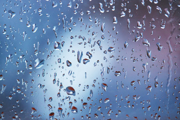 rain droplets on glass over calm colorful background. business backdrop.