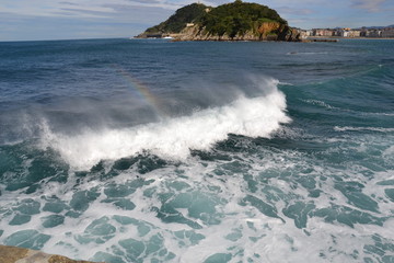 rainbow sparkles in the spray over the waves in the bay de la Concha, San Sebastian