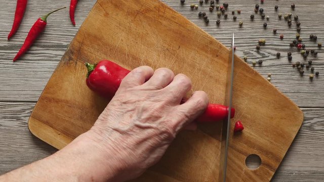 Using Knife To Cutting Ramiro Red Hot Pepper On Cutting Wooden Board. Top View. Close Up..