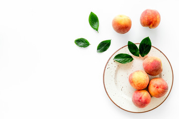 Summer fruits. Ripe red peaches on plate on white table top-down copy space