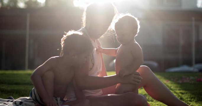 Family outside in home garden with sunlight lens-flare, dreamy scene of mother with children