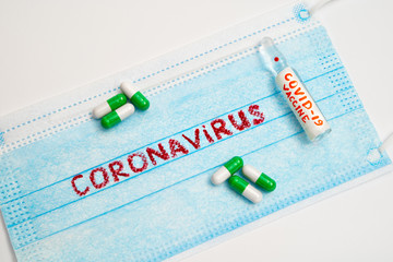 COVID-19. 2019 Novel Coronavirus (2019-nCoV). Virus epidemic. Protective medical face mask to prevent infection by airborne droplets. antibiotic pills and vaccine ampoule on white background