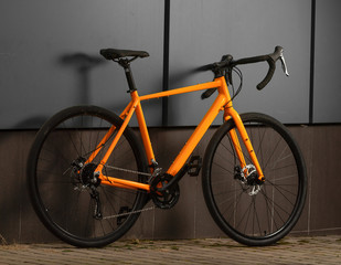 Gravel bicycle. Orange bike for offrad cycling on grey background.