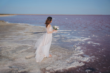 Fototapeta na wymiar sensual bride in a wedding dress on the seashore with the wind in her hair. front view.