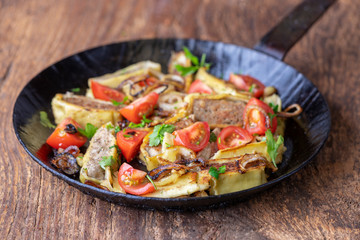 swabian maultasche with onions in an iron pan