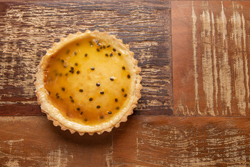 Homemade passion fruit pie with and a golden crust, on wooden background