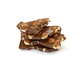 A broken pieces of chocolate with hazelnuts isolated on white background. Milk chocolate tiles with nuts isolated on white.