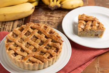 Homemade banana pie with cinnamon and a golden crust, on a wooden background