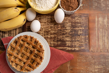 Homemade banana pie with cinnamon and a golden crust, on a wooden background