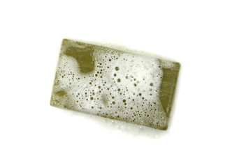 Hand made Olive Soap bar with foam isolated on white background. Wet bar of soap.