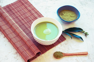 Matcha green tea in a cup on a bamboo tablecloth. Japanese tea ceremony concept. Top view, close up.