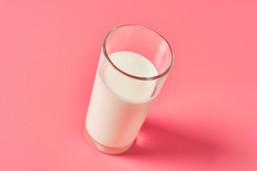 Full glass of fresh milk on pink background