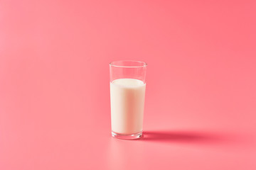 Full glass of fresh milk on pink background