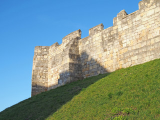 Fototapeta na wymiar a view of the ancient medieval city walls of york with grass covered embankment and blue sky