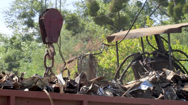 4k footage of big industrial magnet on the junkyard lifting iron and loading it in metal container. Concept of metal recycling