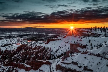 Poster Wide-angle landscape shot of the beautiful Bryce Canyon National Park covered in snow during sunset © Martin Broen/Wirestock