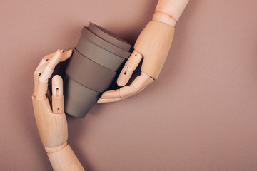 Wooden hand holding reusable cup of coffee. Concept of plastic-free and zero waste living