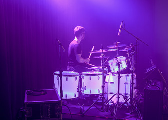 A young drummer playing on his percussion instrument in a fantastic light