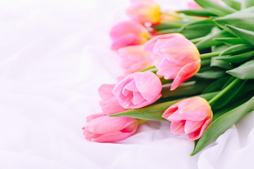 Bouquet of pink tulips on white bed.