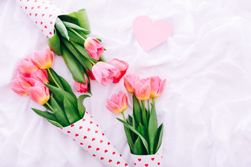 Obraz premium Three little bouquets of pink tulips on white bed.