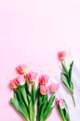 Pink tulip flowers and confetti on pink background. Flat lay, Top view.