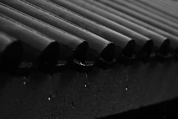  Gotas de agua congeladas cayendo de un techo tejado con un contraste alto blanco y negro, generando la sensaci&oacute;n de nostalgia