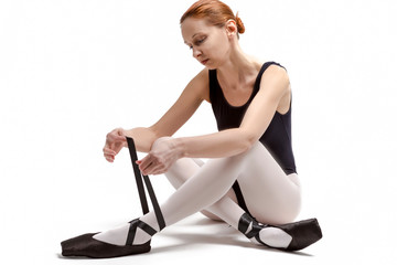 Sport Ideas. Portrait of Tranquil Caucasian Professional Ballet Dancer in Body Suit  and Pointes Shoes Posing Against White Background.