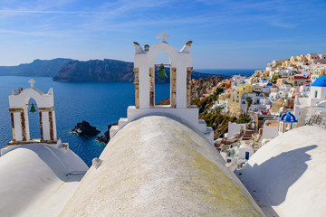 Fototapeta na wymiar Blue domed church and bell tower facing Aegean Sea in Oia, Santorini, Greece