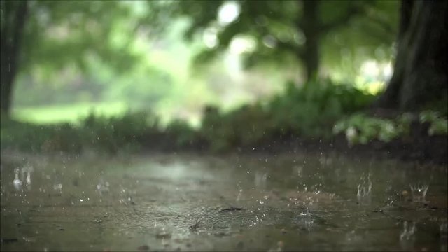 Stunning steady satisfying close up slow motion shot of downpour rain drops falling on pavement asphalt concrete road