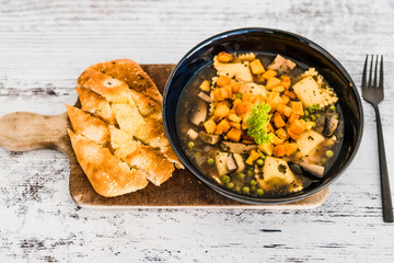 vegan ravioli with vegetable broth peas and pumpkin and side of garlic bread