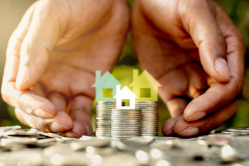 The coins are placed together and there is a small white paper house on top. As the two men's hands are encircled.