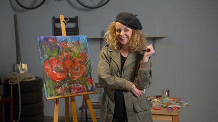 Painter stands on the background of her picture and smiles