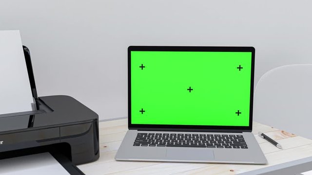 Computer mock-up with green screen for your text. Laptop and printer blank screen placed on a wooden desk.