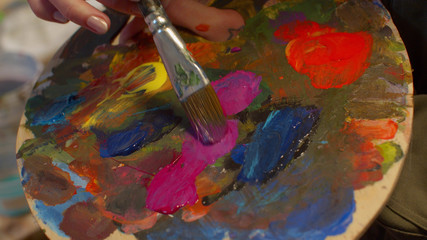 Woman mixes paints on the art palette