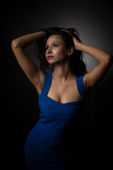 Fashion portrait of an young and attractive Indian Bengali brunette girl with blue western dress in front of a black studio background. Indian fashion portrait and lifestyle.