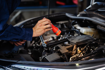 male mechanic holding and shining flashlight to checking car engine problem