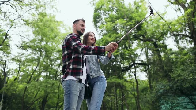 A guy with a girl on a date do a joint selfie on the background of trees in the park.