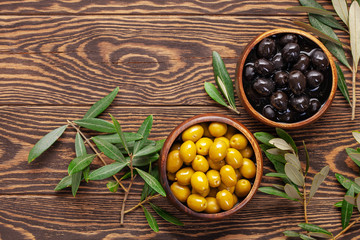 Black and green Olives, olive tree branch and ciabatta bread on dark wooden table. Top view. Flat...