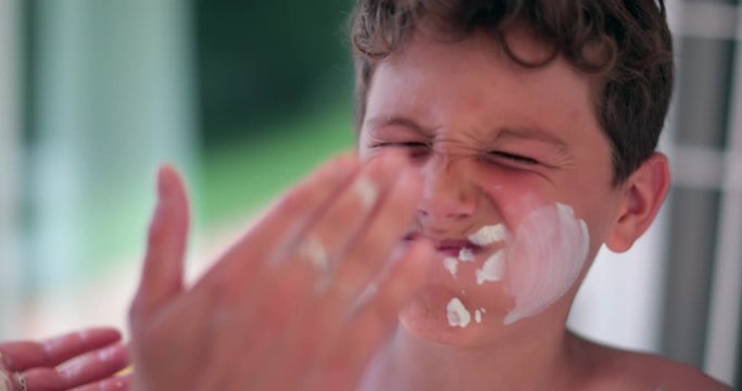 Mother applying sunscreen lotion to child boy face. Parent applies sunblock to kid