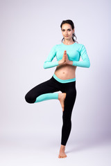 Beautiful sporty lady in fitness leggings and top doing yoga and meditation on a white isolated background. Healthy and Fitness Lady Concept