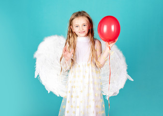 Kids Valentines Day. Cute toddler girl in white wings as Cupid. Angel kid with blonde curly hair....