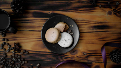 Top view of Coffee macarons on black plate with purple ribbon, coffee bean and dry roses decorated