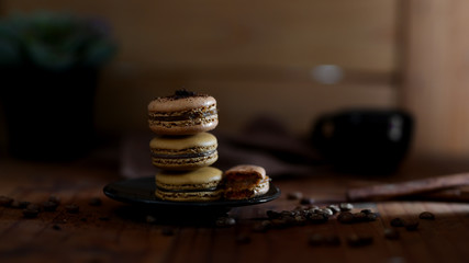 Cropped shot of  macarons on black plate with coffee bean decorated on rustic table