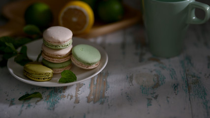 Cropped shot of green fruit flavours  macarons on white plate on vintage table