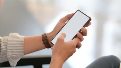 Close up view of businessman texting on smartphone while sitting on couch