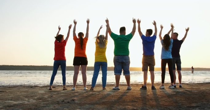 People in colored T-shirts waving with raised hands, friendship, unity and equality concept.